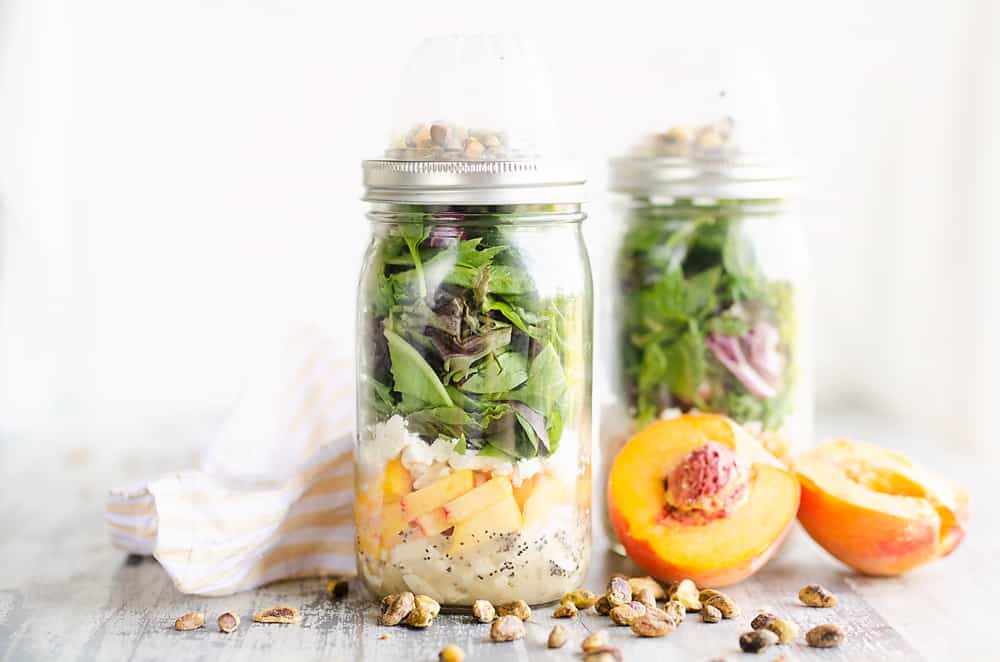 Chicken Peach Salad in a Jars on a table with pistachios and half peaches