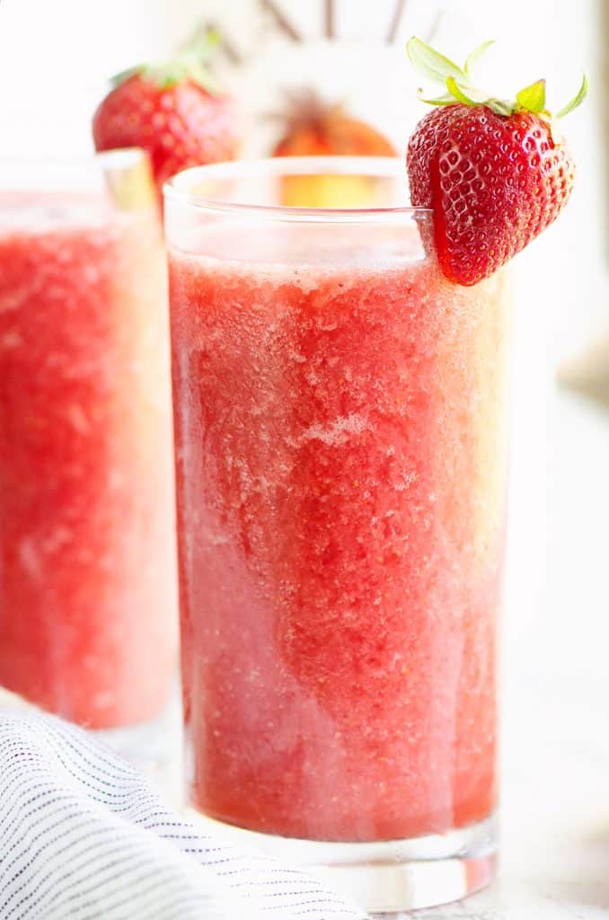 Frozen Strawberry Malibu Kombucha Cocktails on table with strawberry on top of glass