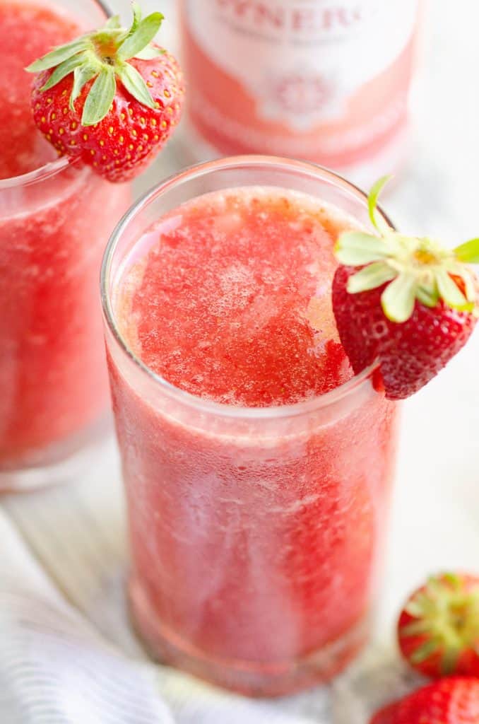 Frozen Strawberry Malibu Kombucha Cocktail on table with strawberry on top of glass and on table