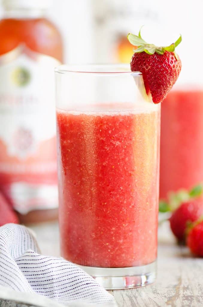 Frozen Strawberry Malibu Kombucha Cocktail on table with jar of kombucha and fresh strawberries