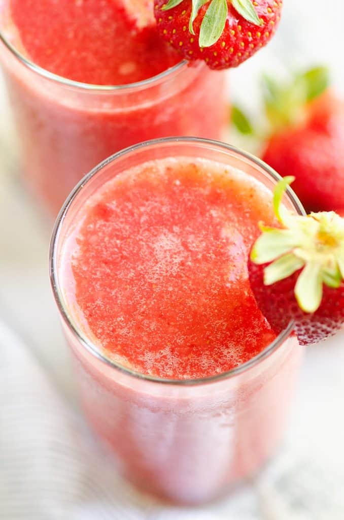 Frozen Strawberry Malibu Kombucha Cocktail with a fresh strawberry on top of glass