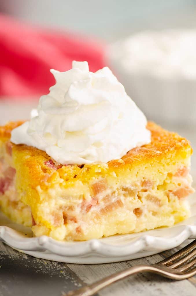 Rhubarb Custard Cake slice topped with whipped cream