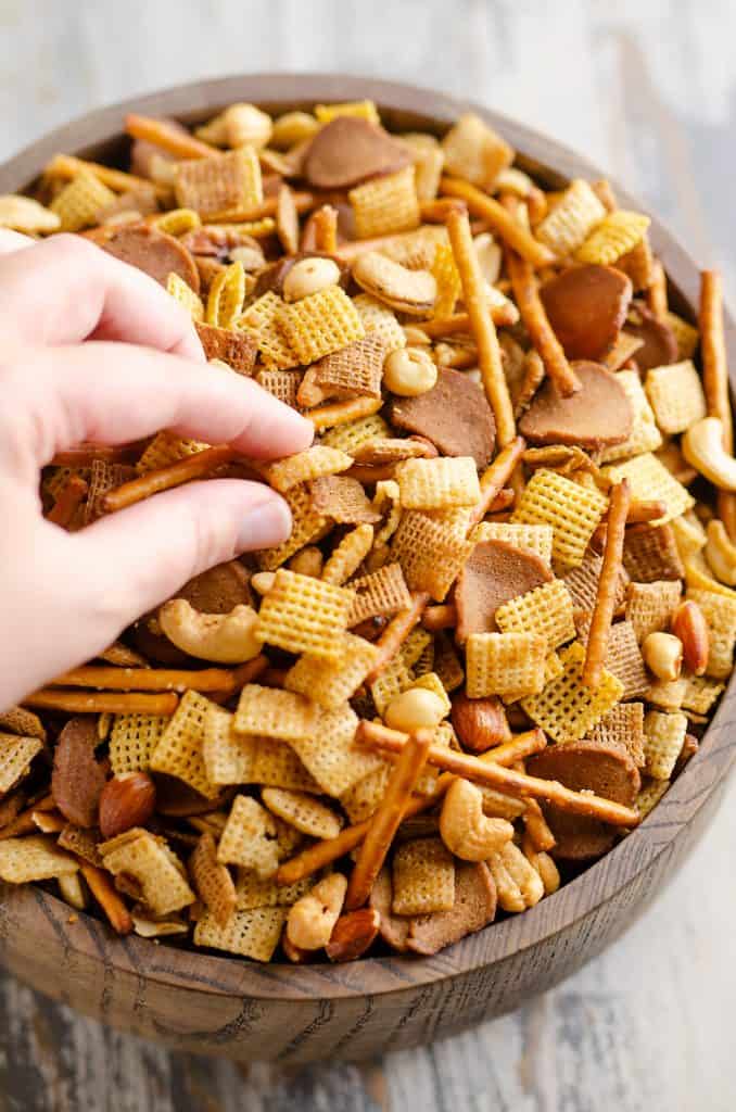 eating buttery snack mix from large wooden bowl