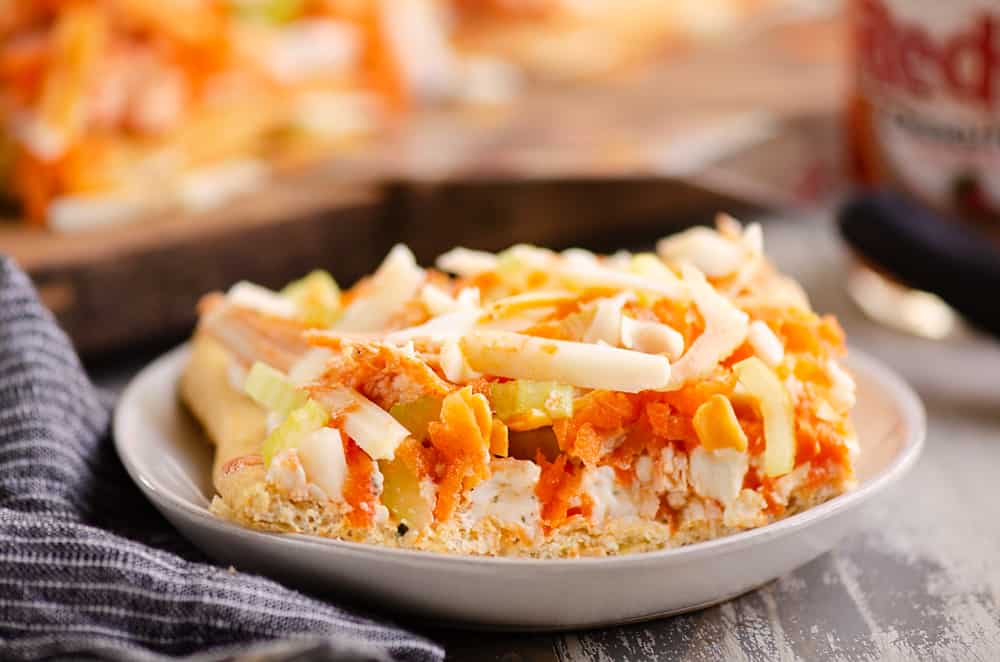 Buffalo Chicken Vegetable Pizza slice on white plate with napkin