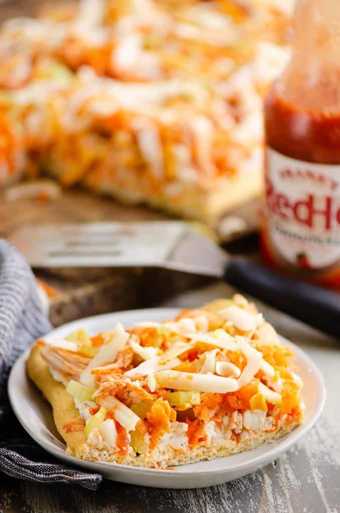 Buffalo Chicken Vegetable Pizza slice on white plate served on table with sauce