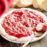 Whipped goat cheese topped with a rhubarb sauce served on a small appetizer plate with a spoon and French bread