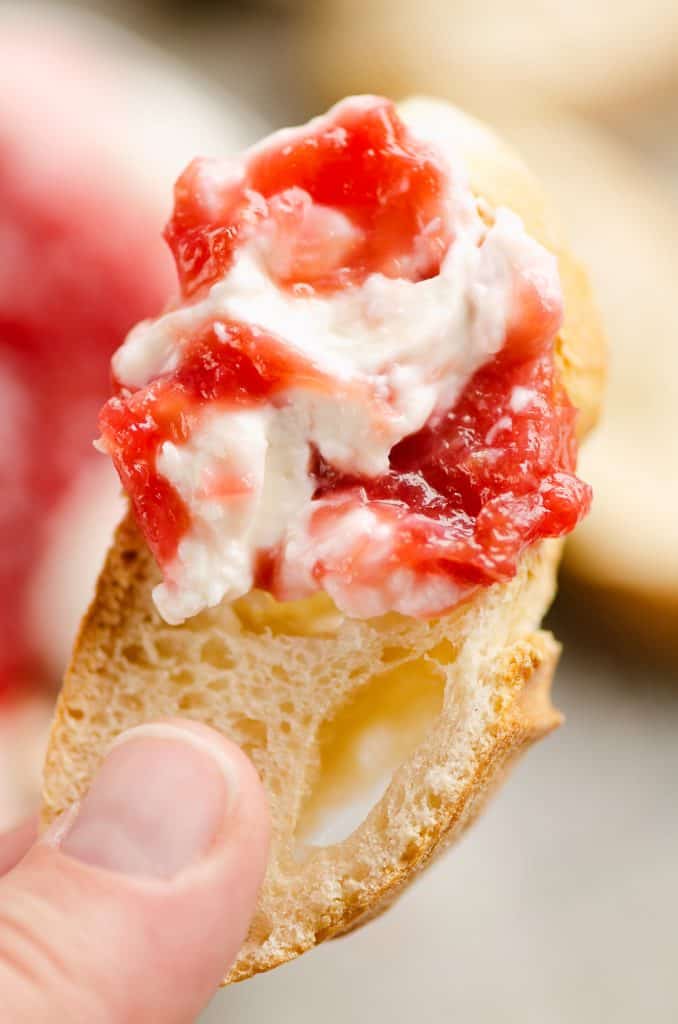 Whipped goat cheese topped with a rhubarb sauce swirled on a piece of French bread