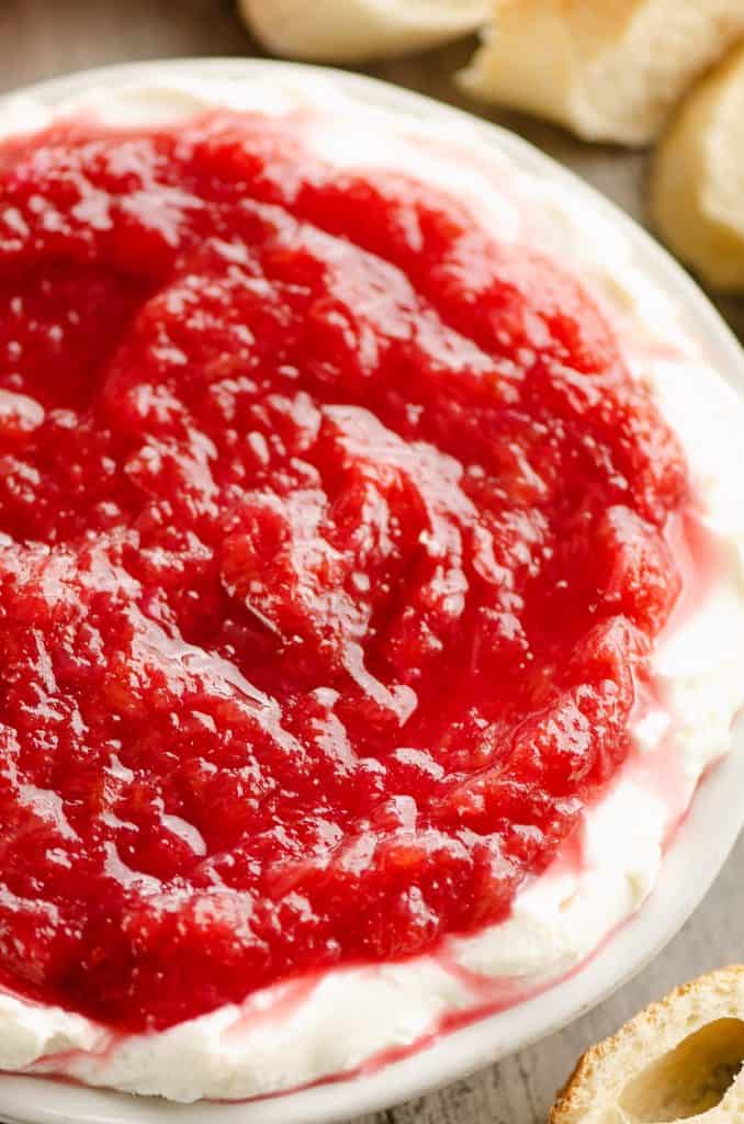 Whipped goat cheese topped with a rhubarb sauce served on a small appetizer plate with French bread