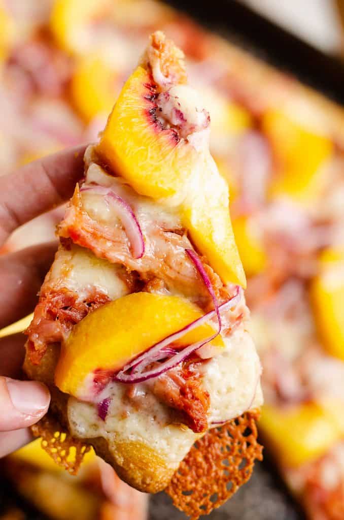 slice of BBQ Peach Pizza held in hand