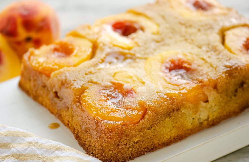 Peach Upside Down Cake on table with fresh peaches