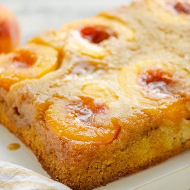 Peach Upside Down Cake on table with fresh peaches