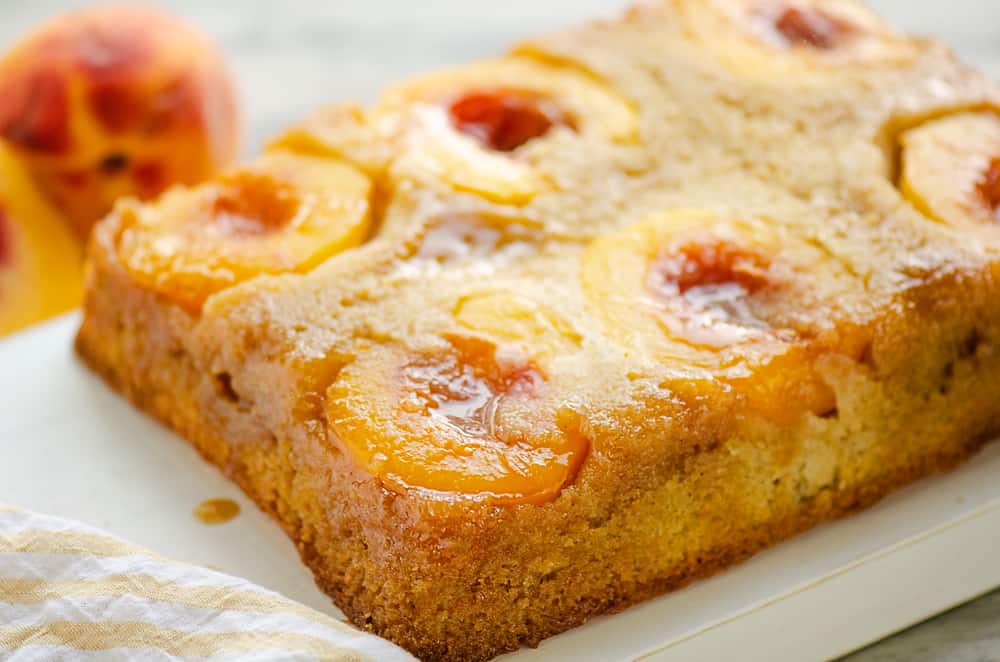 Peach Upside Down Cake on table with fresh peaches