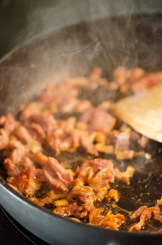Bacon in skillet with wooden spatula