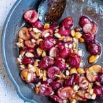 Cherries and almonds in cast iron skillet with spoon