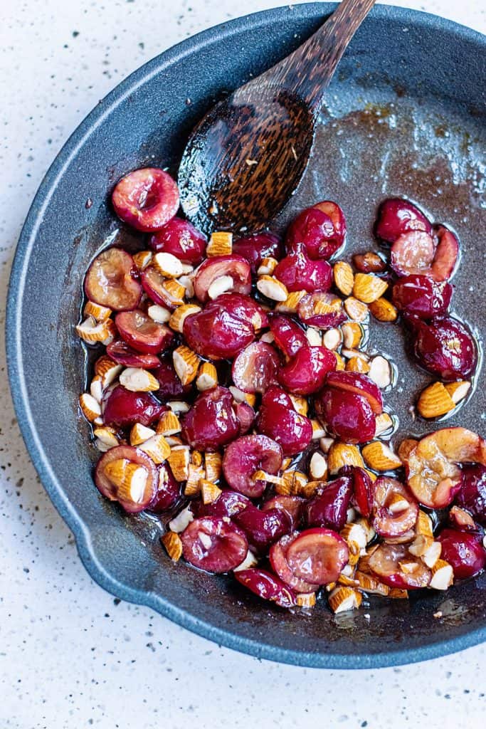 Cherries and almonds in cast iron skillet with spoon