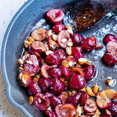 Cherries and almonds in cast iron skillet with spoon