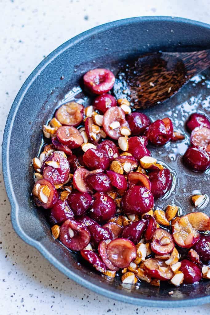 Cherries and almonds in cast iron skillet with spoon