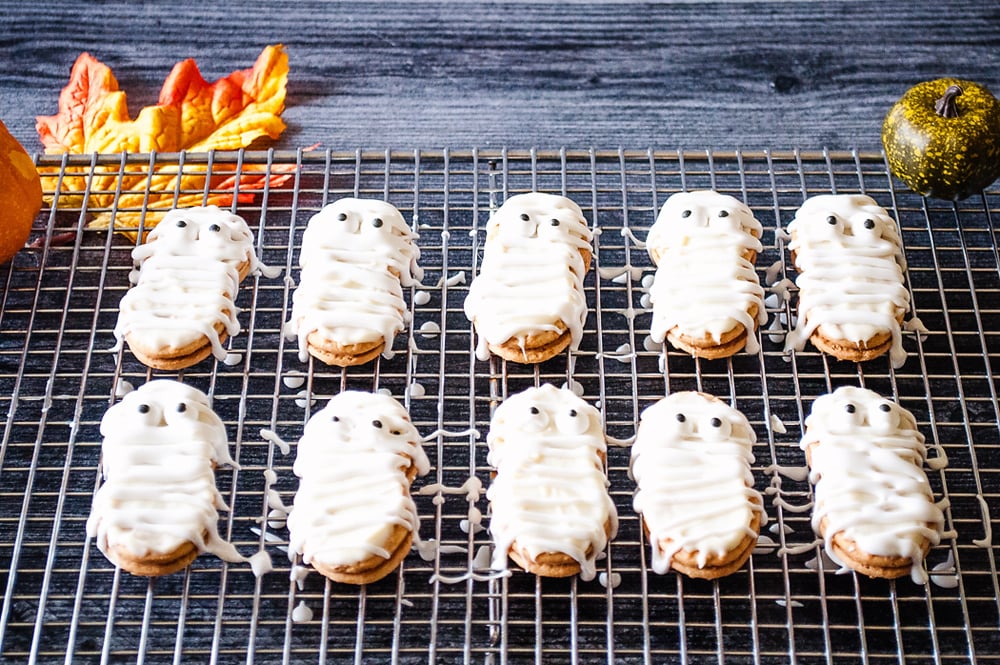 Mummy Nutter Butter Cookies drizzled with frosting on cooling rack