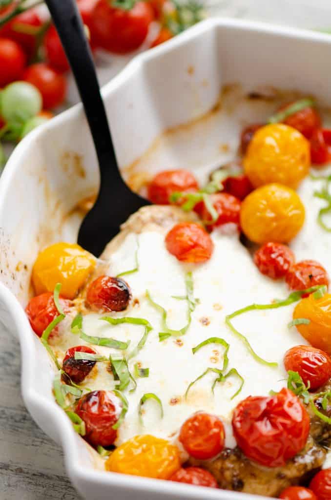 Honey Balsamic Caprese Chicken scooped out of white baking dish with black fork