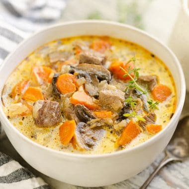 Creamy Mushroom Beef Soup in white bowl with stripe napkin