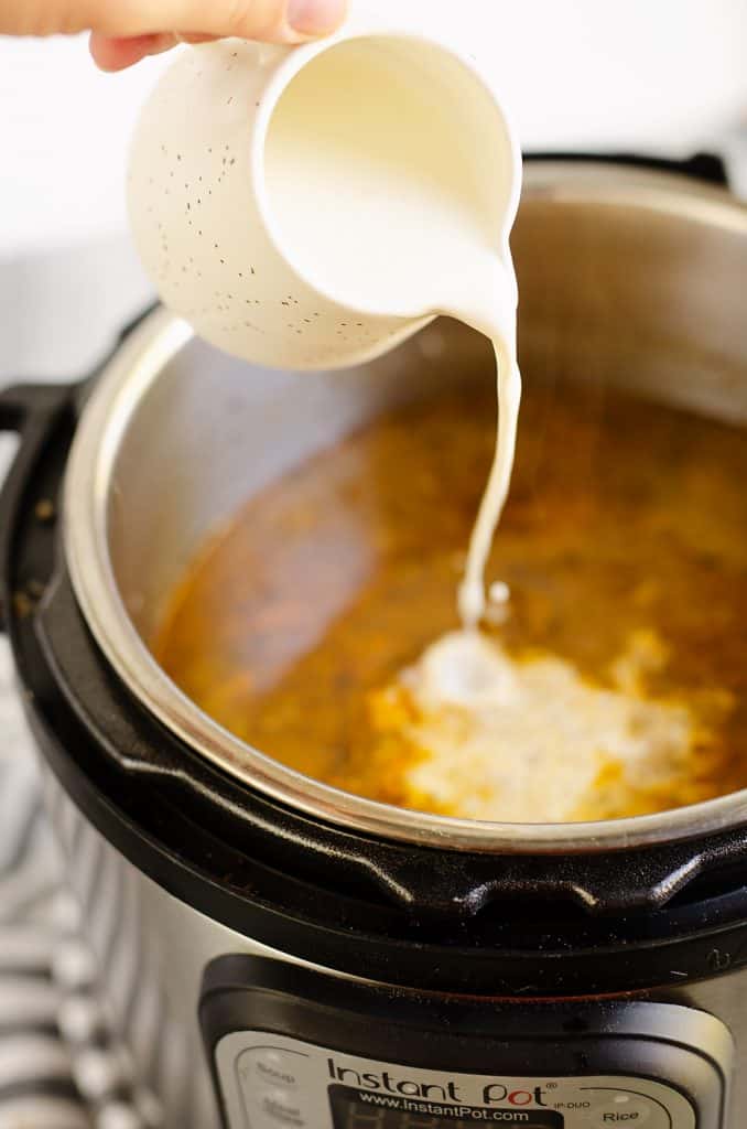 cream being poured into pressure cooker with Creamy Mushroom Beef Soup