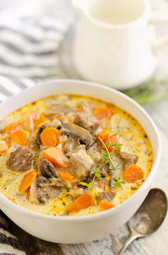 Creamy Mushroom Beef Soup in white bowl on table with cream