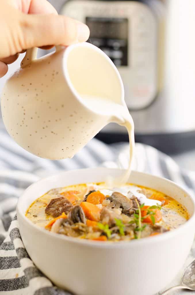 cream being poured into bowl of Creamy Mushroom Beef Soup