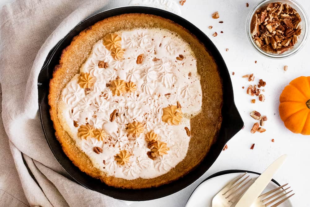 Pumpkin Spicy Dutch Baby on white table with pumpkin and pecans