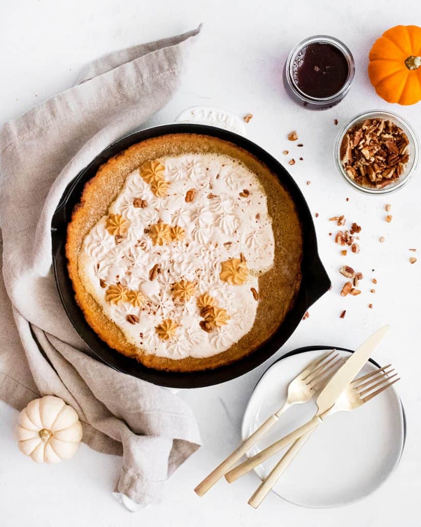 Pumpkin Spicy Dutch Baby on white table with pumpkins, silverware, pecans and maple syrup