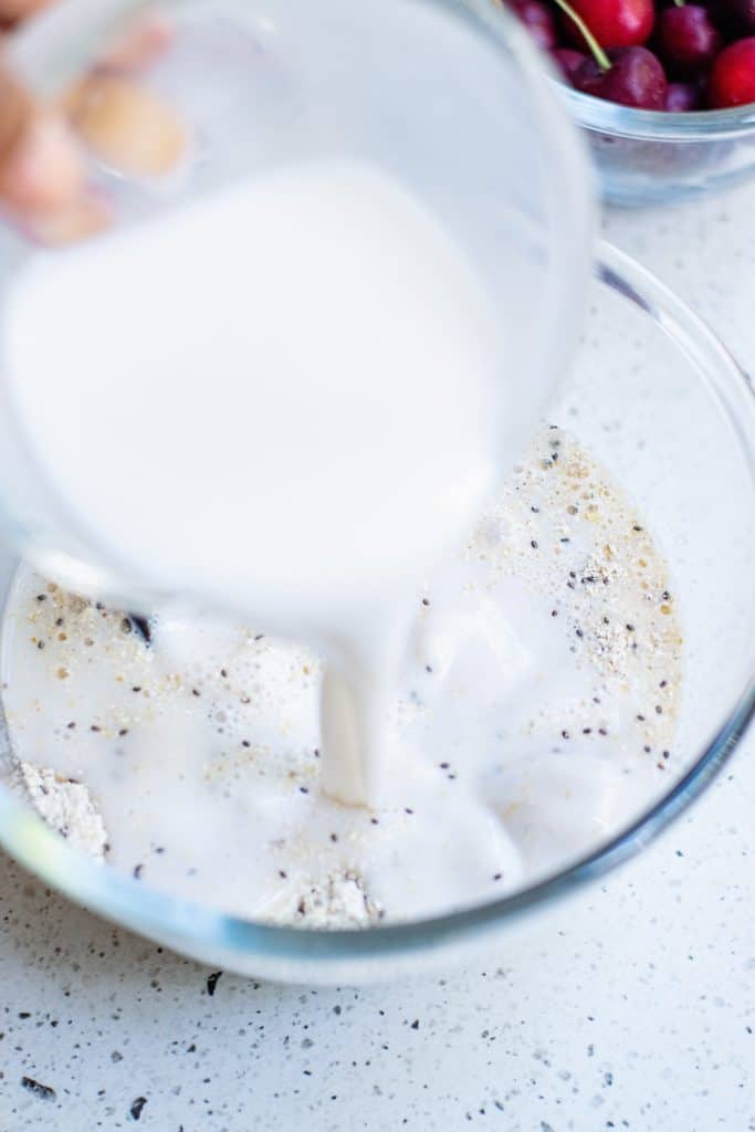 Oatmeal pancake batter in bowl with milk poured in