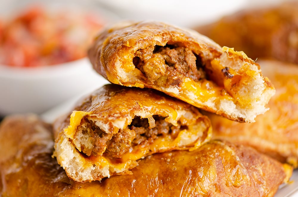 Air Fryer Taco Calzones broken in half stacked on cutting board