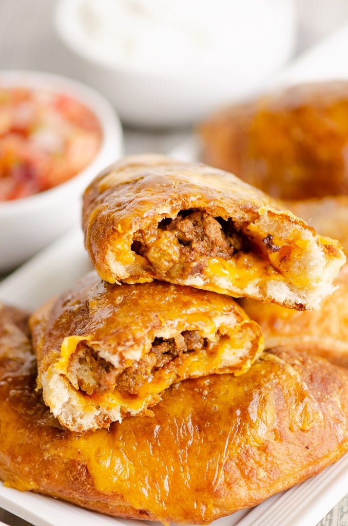 Air Fryer Taco Calzones broken in half stacked on cutting board