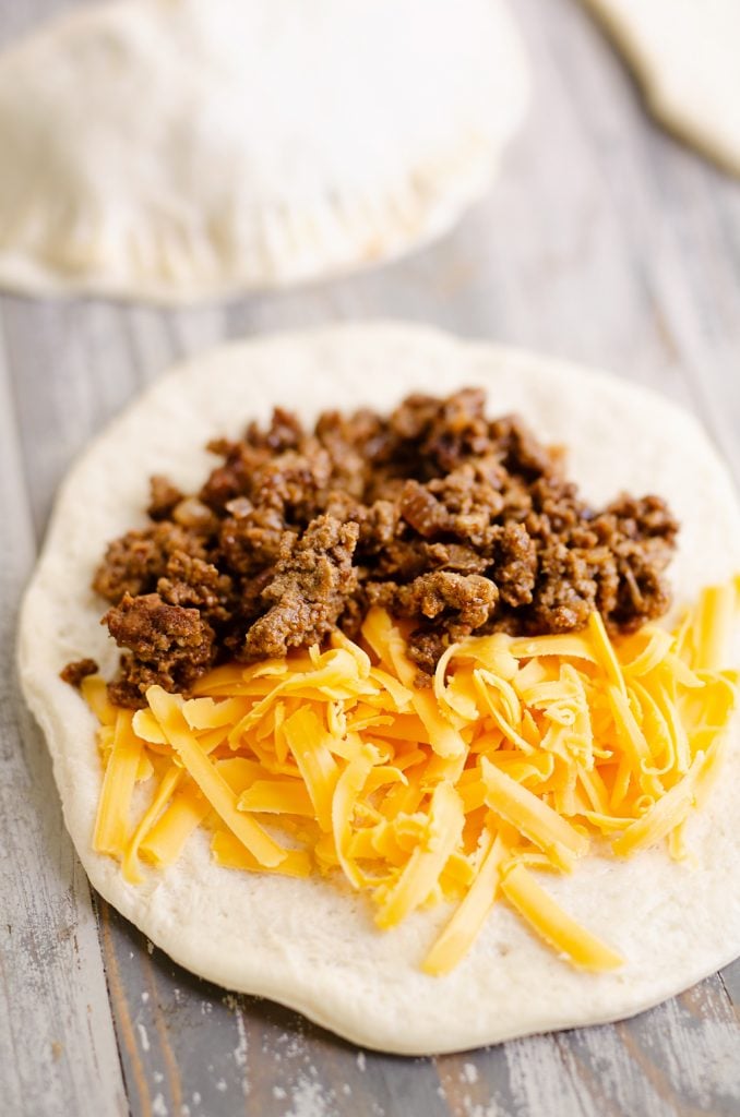 taco meat and cheese on circle of pizza dough