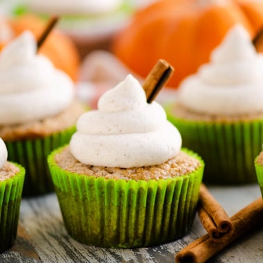 fall spiced cupcakes with buttercream swirls on table with cinnamon and pumpkins