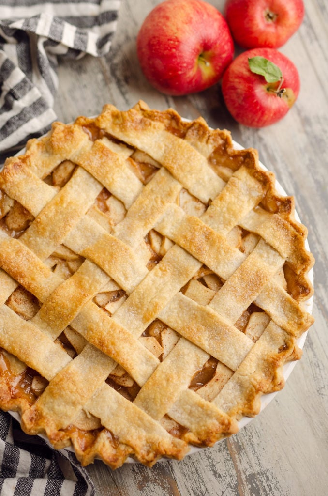 Old Fashioned Apple Pie with lattice crust on table with apples