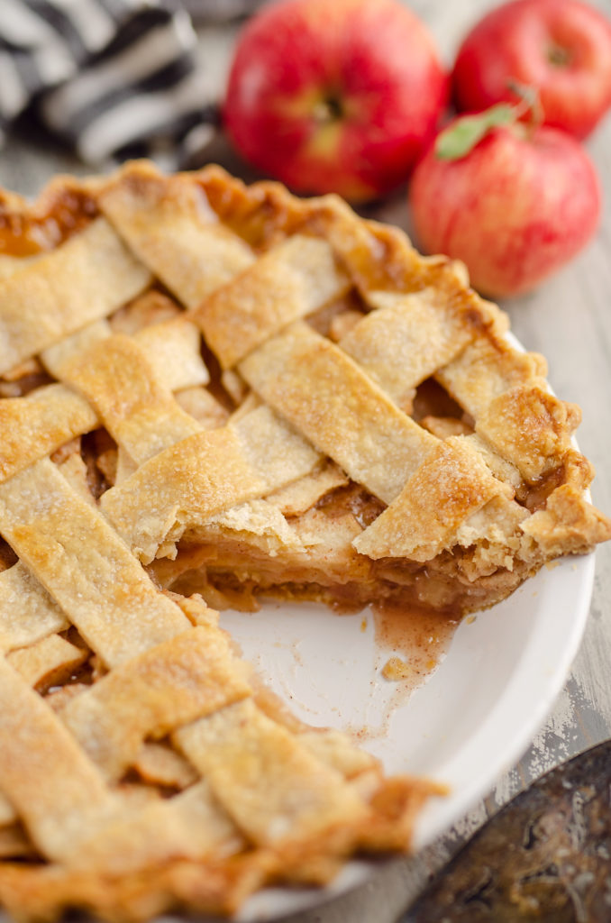 Old Fashioned Apple Pie with lattice crust in white pie plate with slice cut out