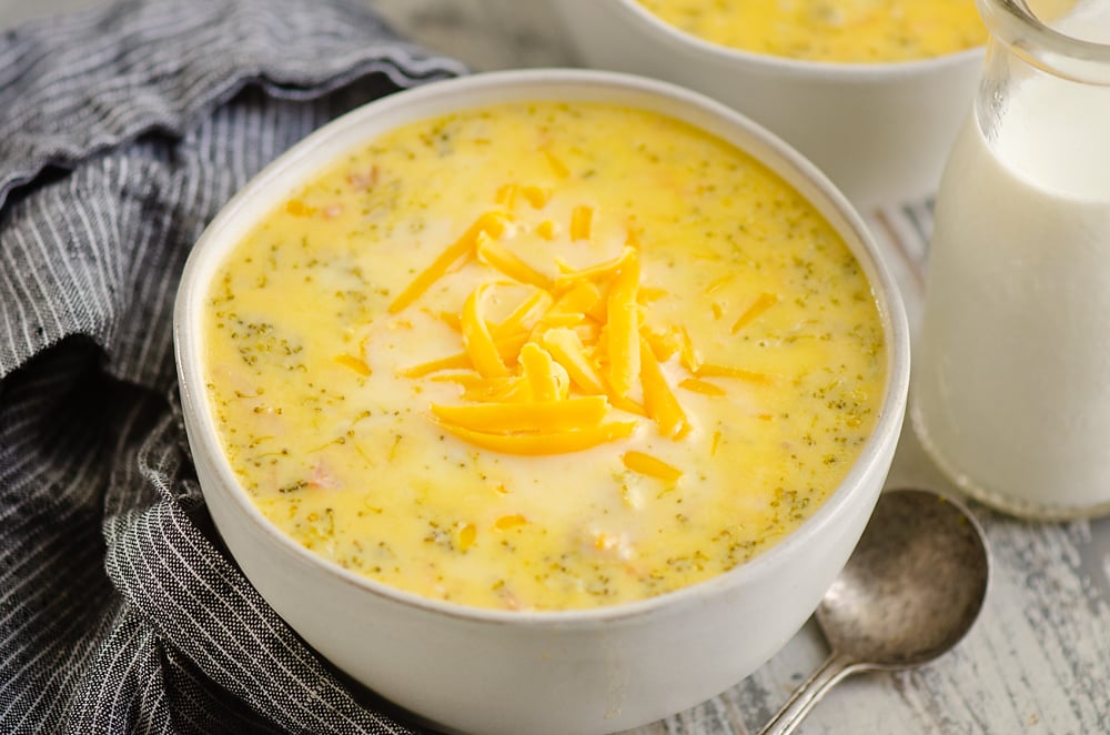 Pressure Cooker Cheesy Ham & Broccoli Soup in white bowl with glass jar of milk