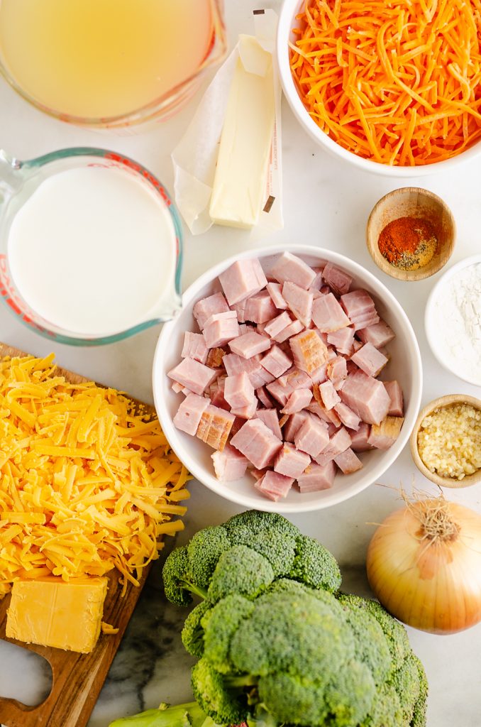 marble table with, chicken broth, milk, broccoli, cheese, carrots, ham and butter