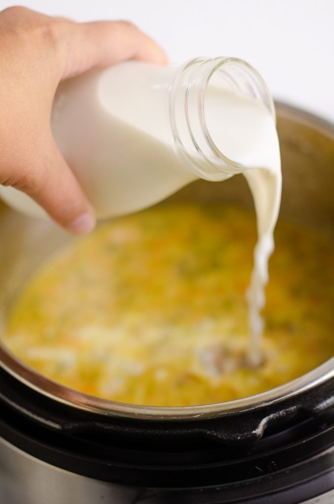 milk being poured into Pressure Cooker Cheesy Ham & Broccoli Soup