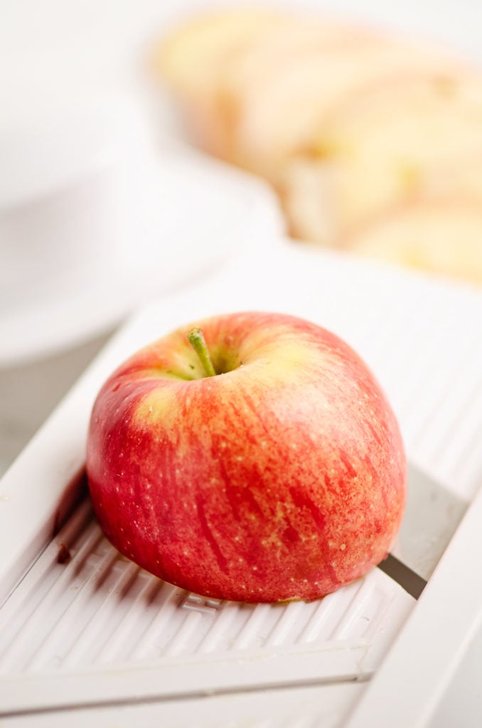 apple on mandolin being sliced