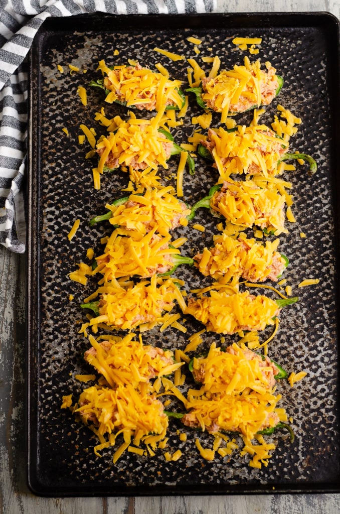 Cheesy BBQ Pork Jalapeno Poppers topped with shredded cheddar on sheet pan