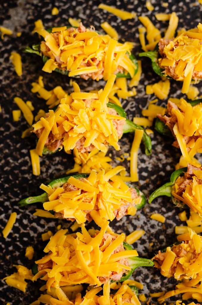 Cheesy BBQ Pork Jalapeno Poppers topped with shredded sharp cheddar