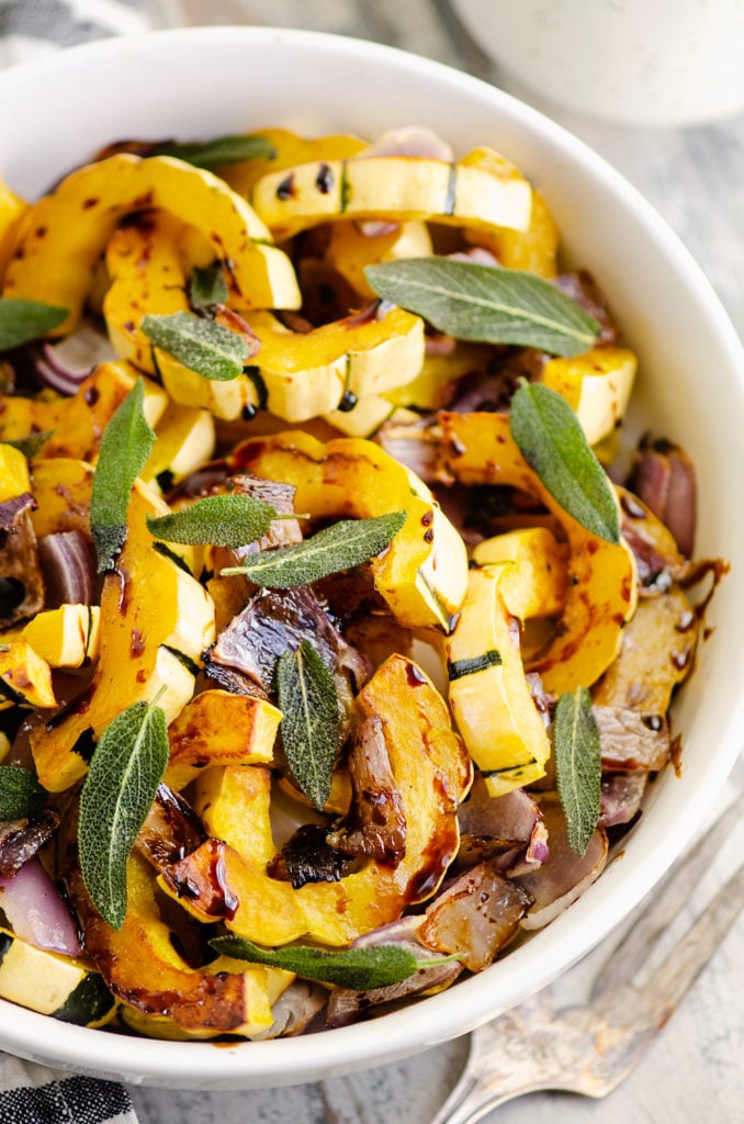 Crispy Sage Roasted Delicata Squash with balsamic glaze in white bowl