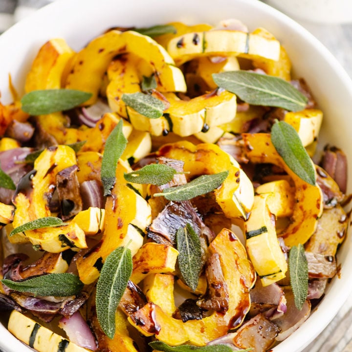 Crispy Sage Roasted Delicata Squash with balsamic glaze in white bowl