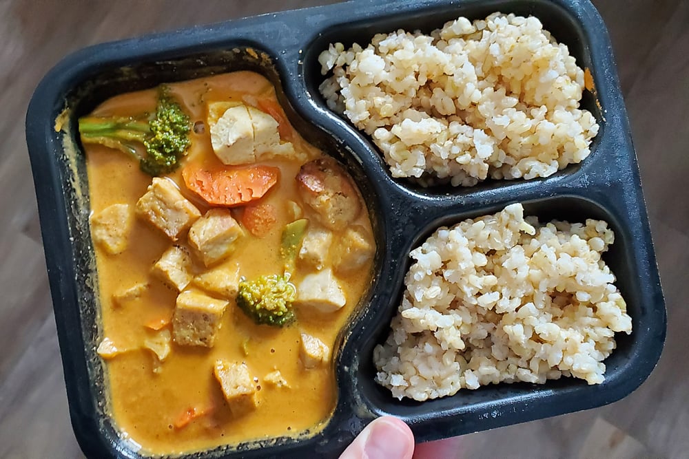 Veestro Red Curry Plant Based meal with brown rice in black microwave container