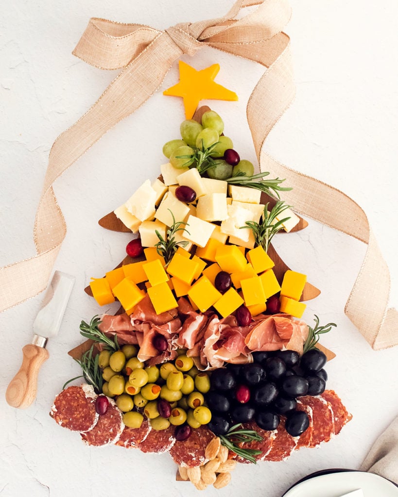 christmas tree cutting board topped with meat and cheese with ribbon