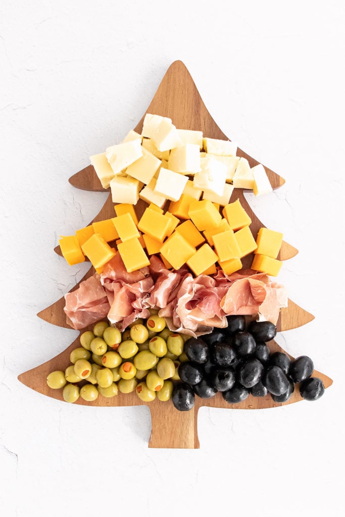 christmas tree cutting board topped with meat olives and cheese
