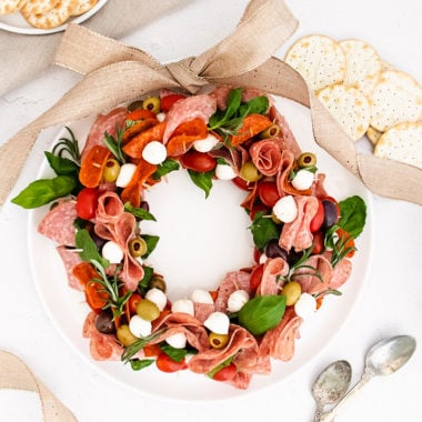 Christmas antipasto wreath on white plate with ribbon