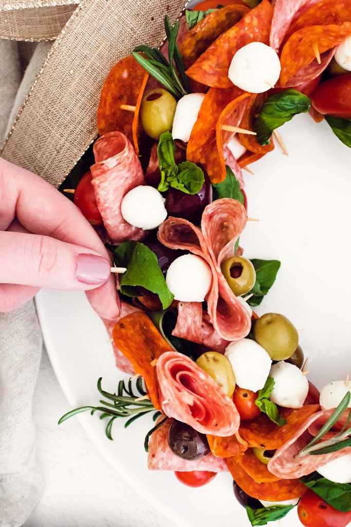 hang grabbing skewer of meat and cheese from antipasto wreath