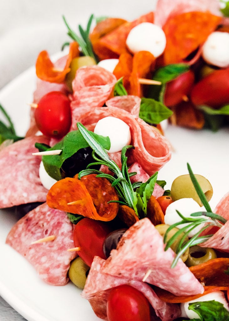 skewers of meat and cheese stacked on white plate with rosemary